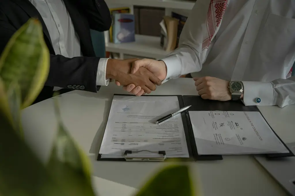 Dos personas se dan la mano sobre un acuerdo firmado